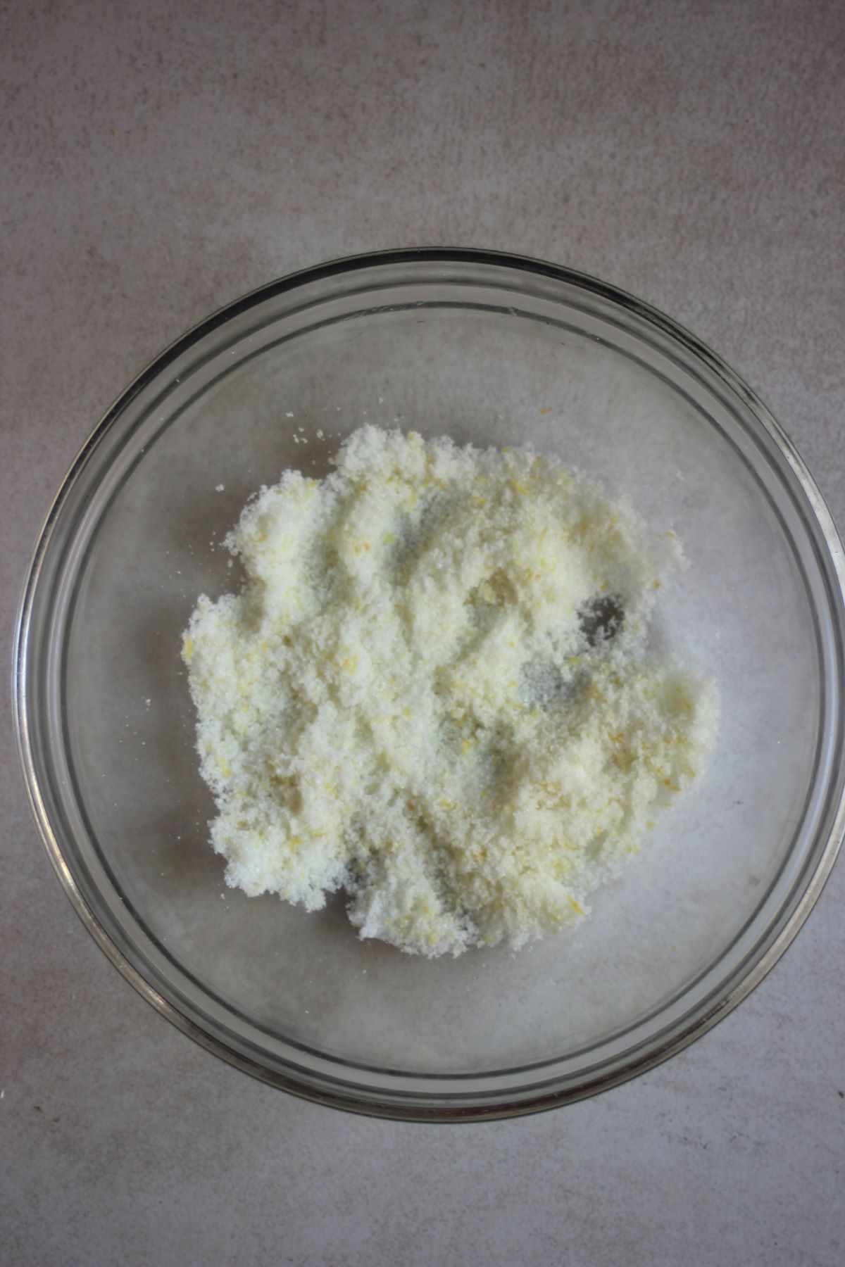 Glass bowl with white sugar and lemon zest.