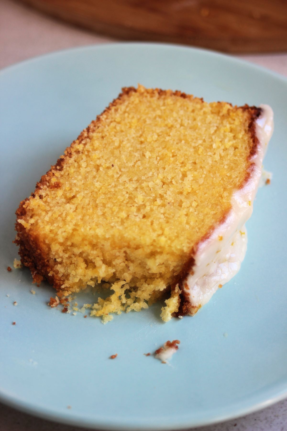 A slice of orange cake with icing on a light blue plate.