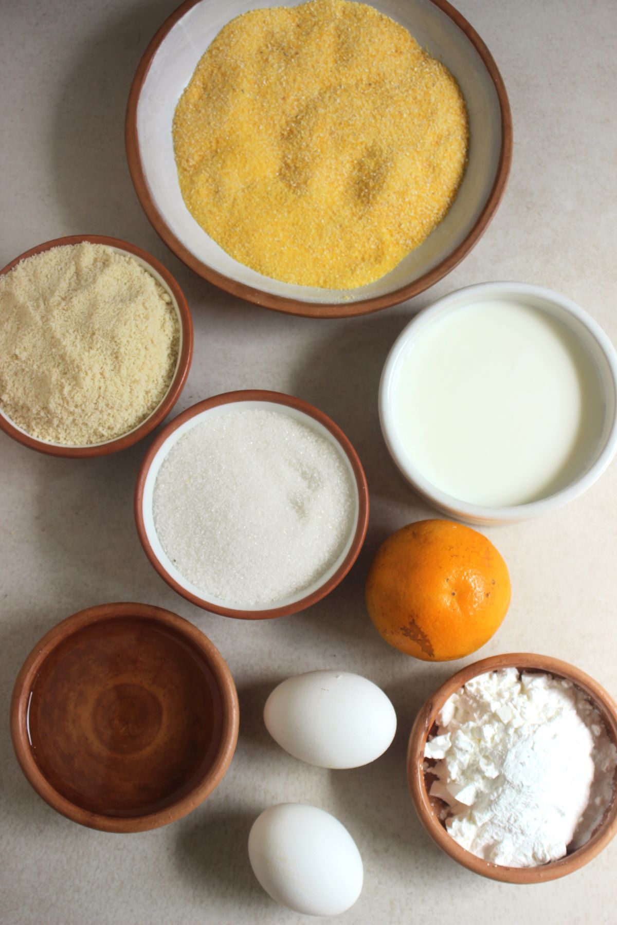 Orange cake ingredients on a white surface seen from above.