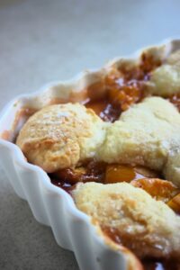 A part of a baking sheet with a peach cobbler seen from close,