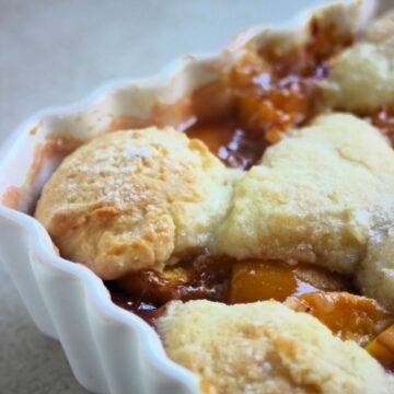 A part of a baking sheet with a peach cobbler seen from close,