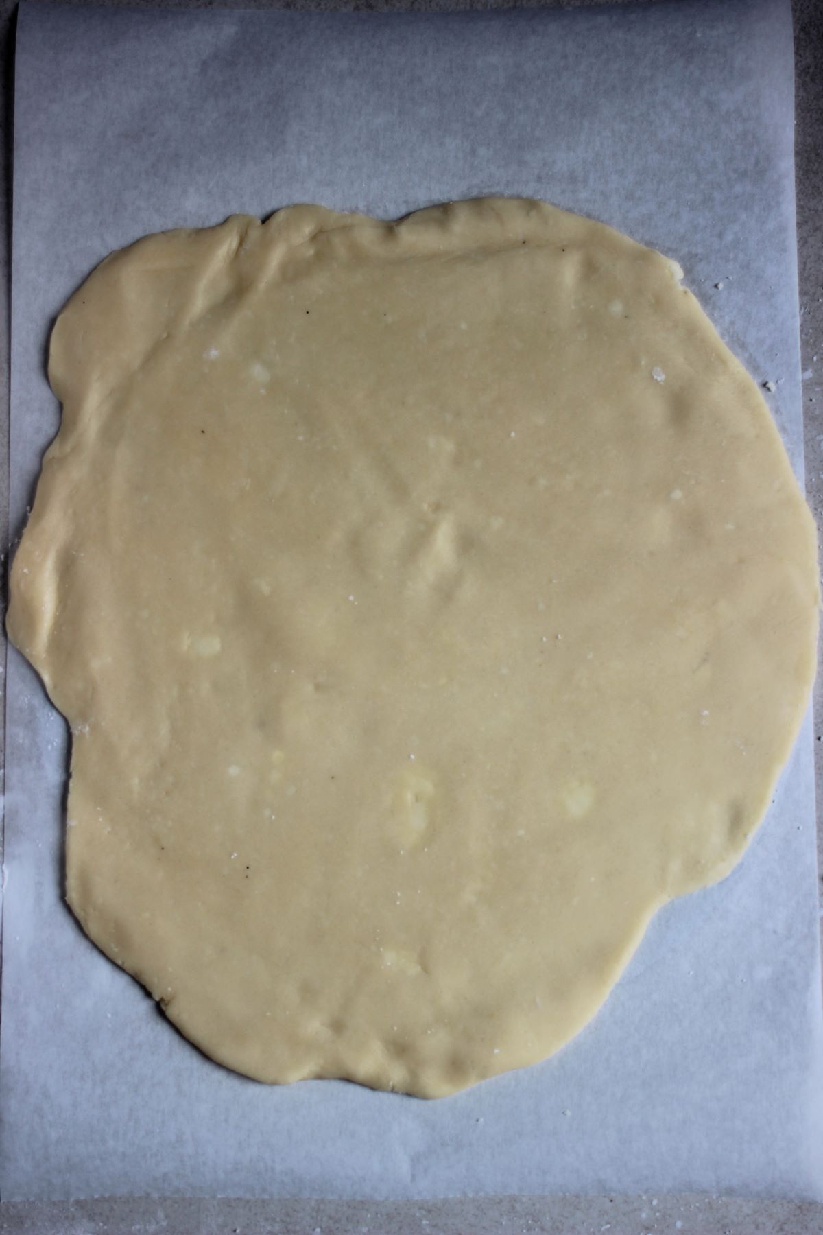 Stretched dough on a piece of parchment paper.