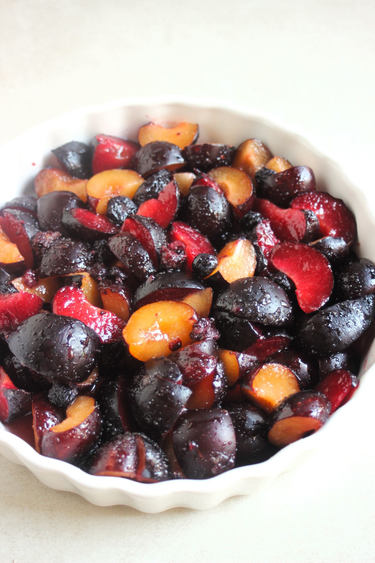 Round baking pan with slices of plums, and mixed berries.