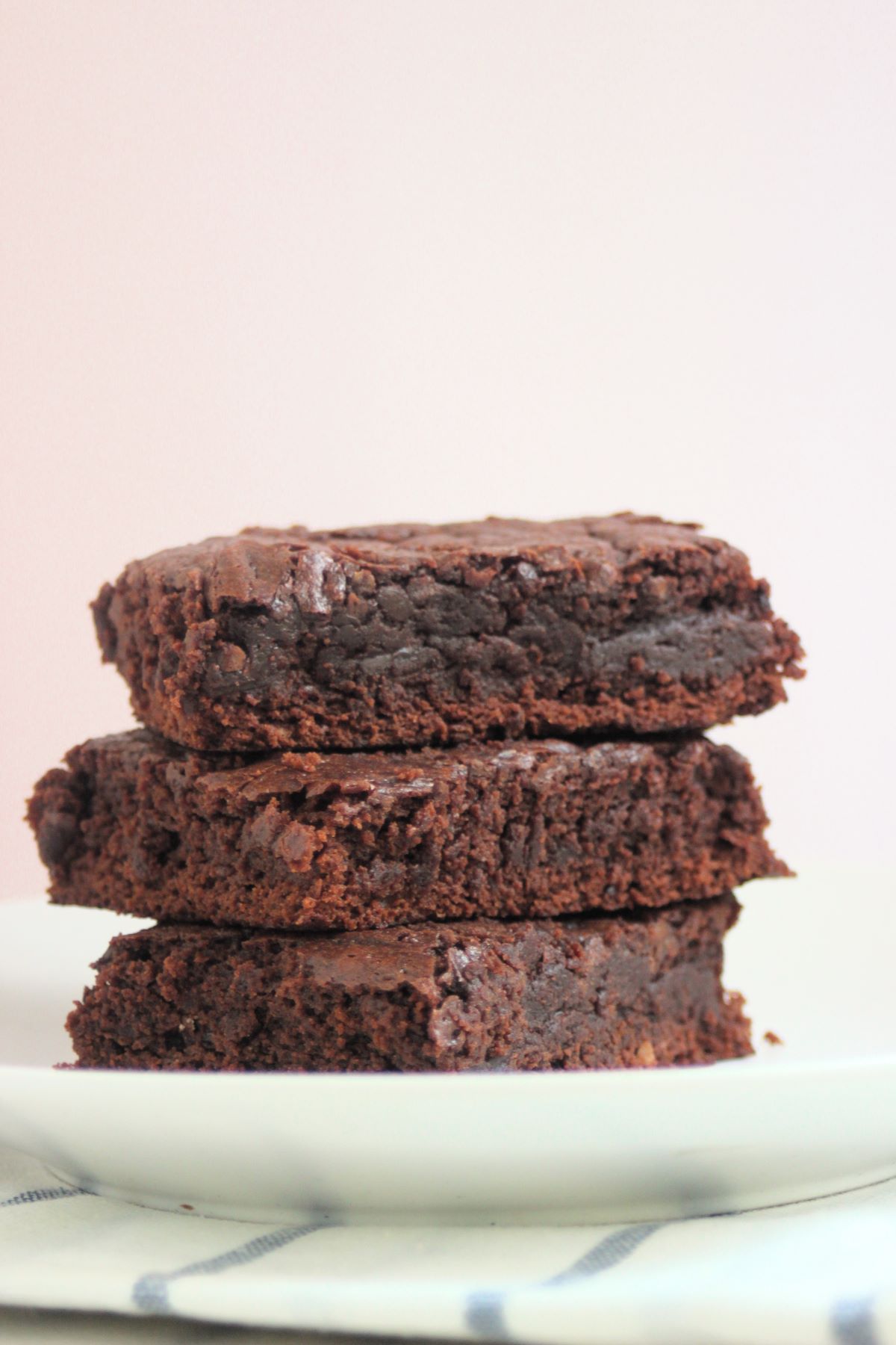 Three brownies stacked on a white plate.