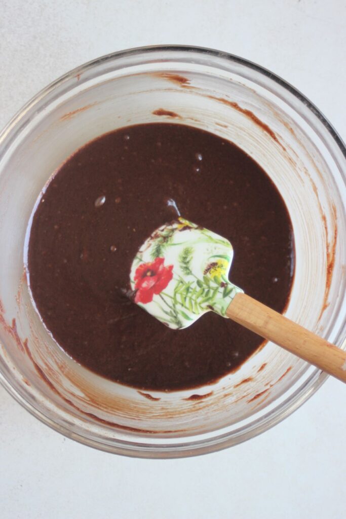 Glass bowl with chocolate mixture and a rubber spatula.
