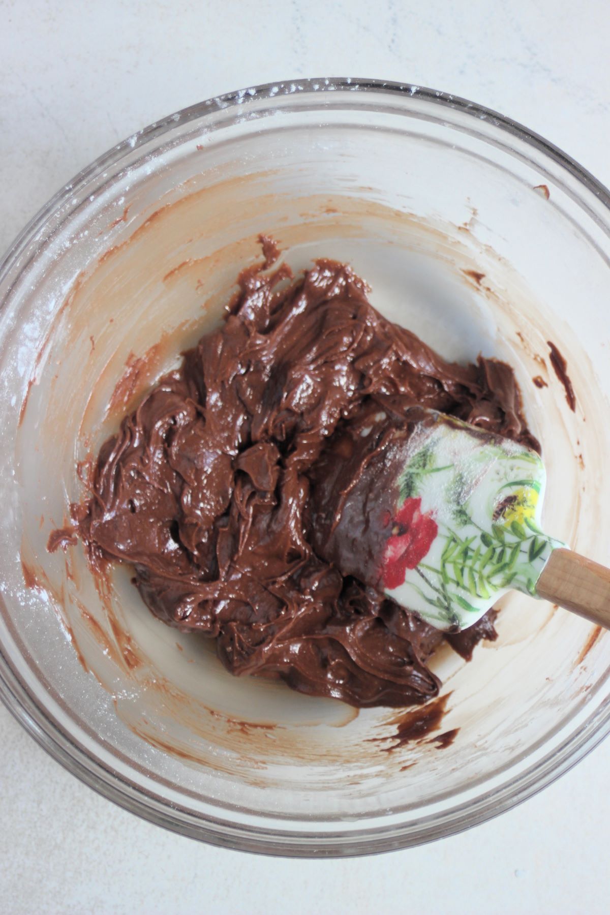 Glass bowl with a chocolate mixture and a rubber spatula.