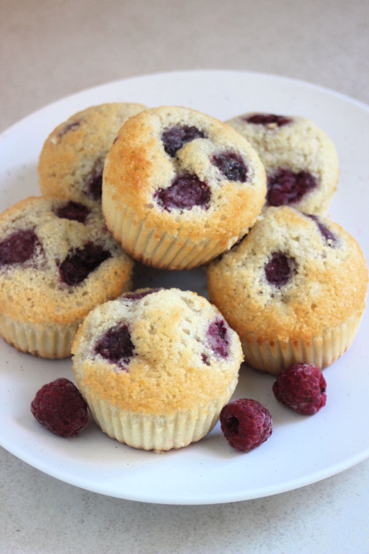 Raspberry muffins on a white plate. Raspberries on the side.