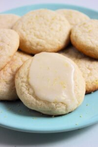 Many cookies on a aqua-green plate. The first cookie seeing is topped with icing.