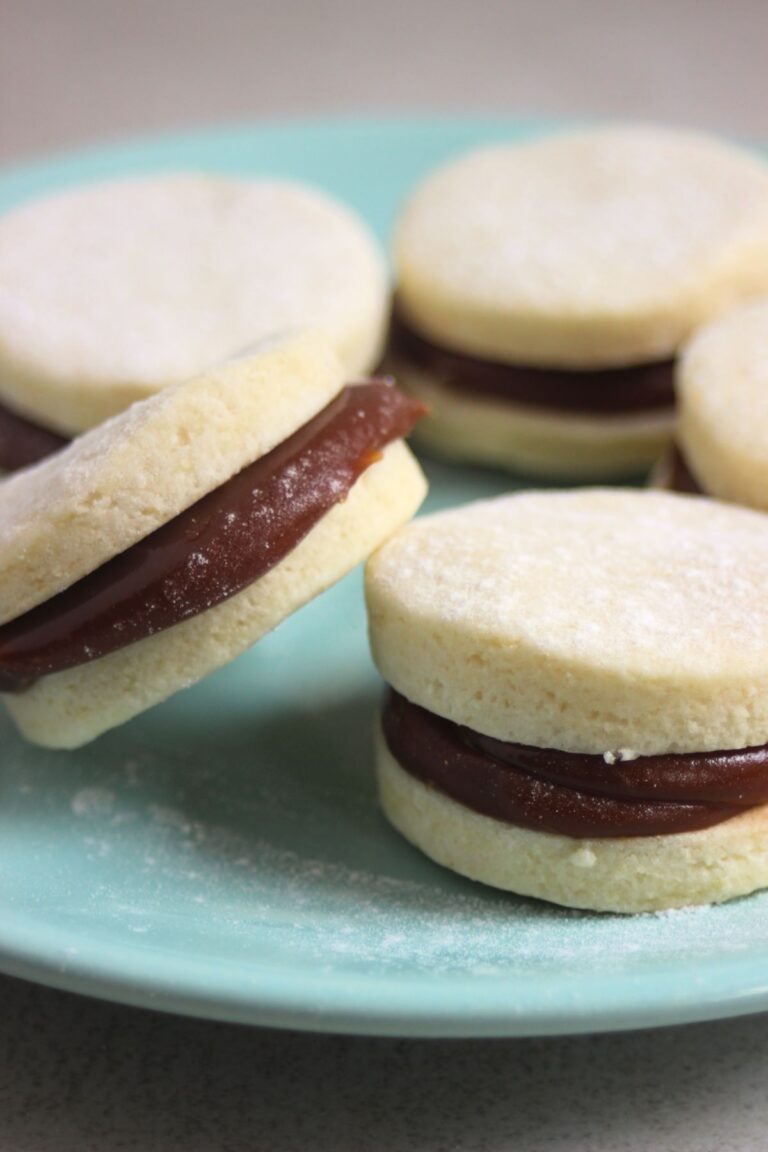 Almond alfajores on a green aqua plate.