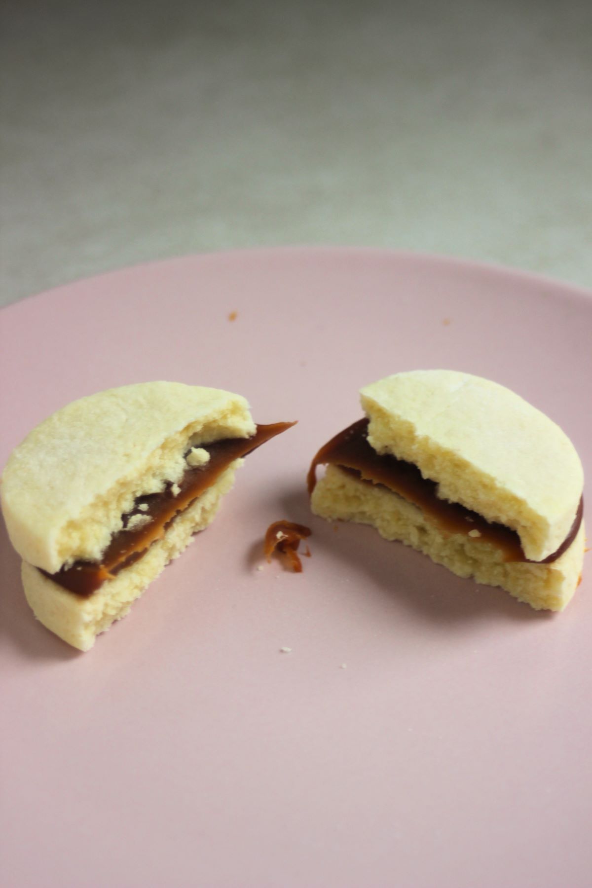 Almond alfajor cut in two pieces on a pink plate