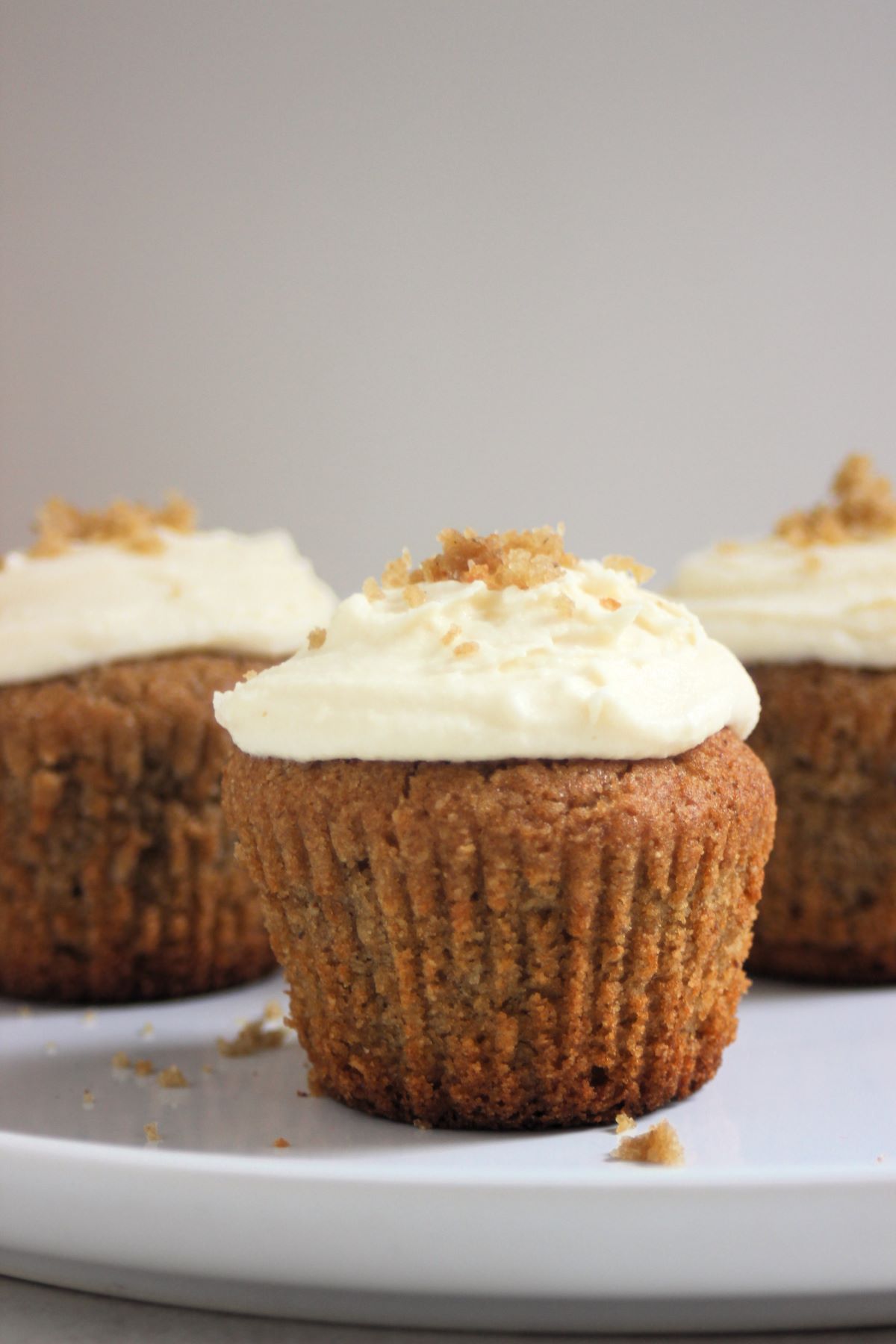 Sweet potato muffins with cream cheese frosting front on a white plate.