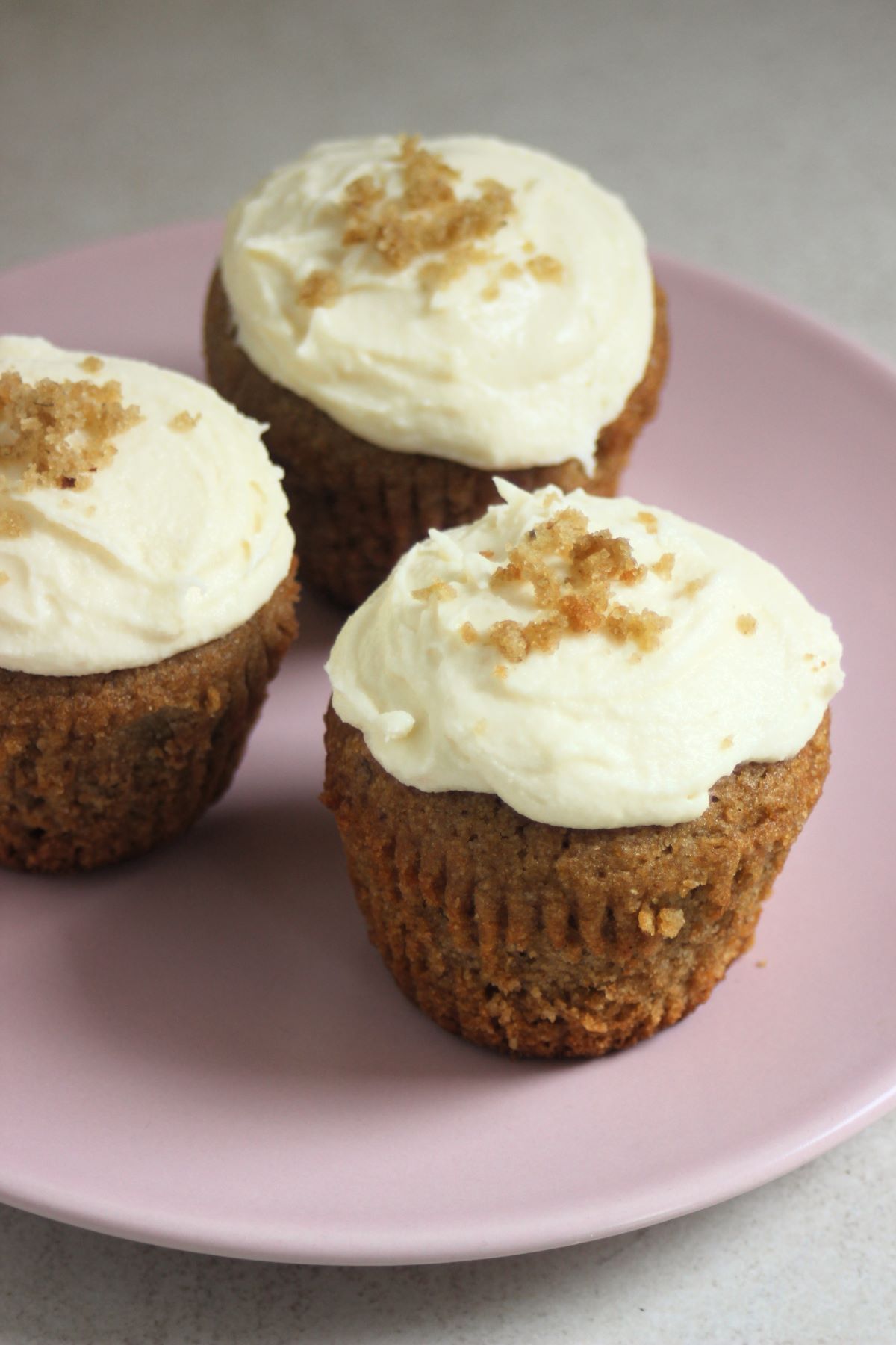 Sweet potato muffins with cream cheese frosting on a pink plate.