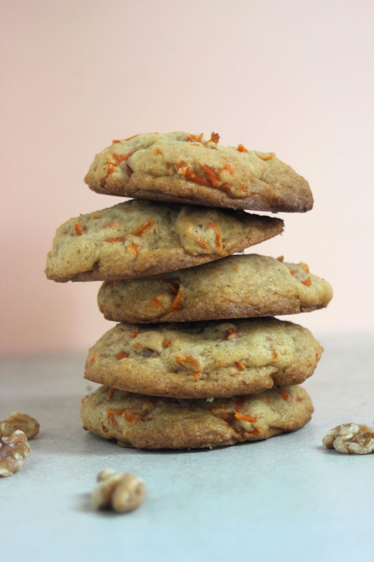 A tower of carrot cake cookies on a white surface, Pink background.