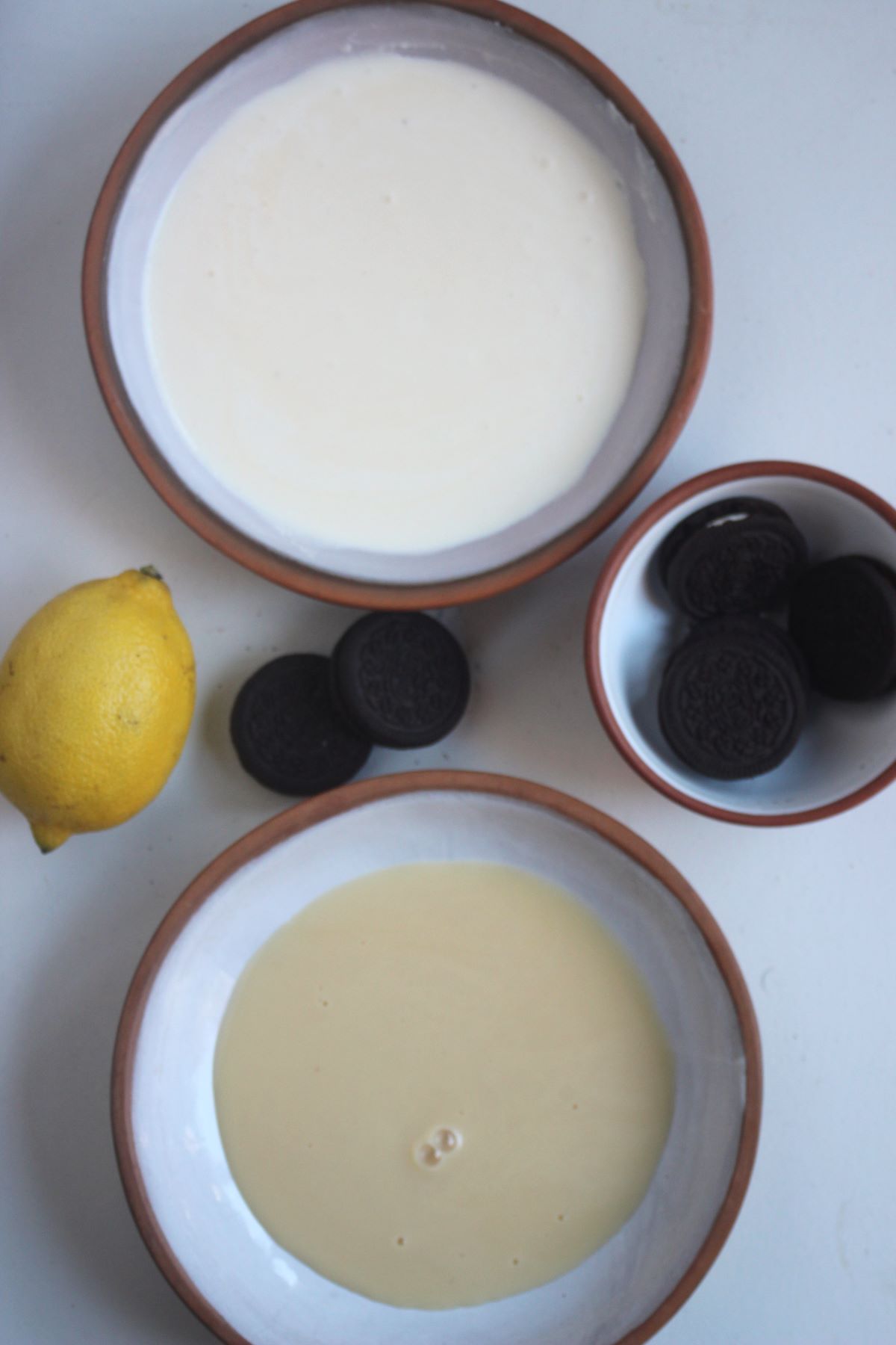 Lemon mousse with Oreos ingredients on a white surface seen from above.