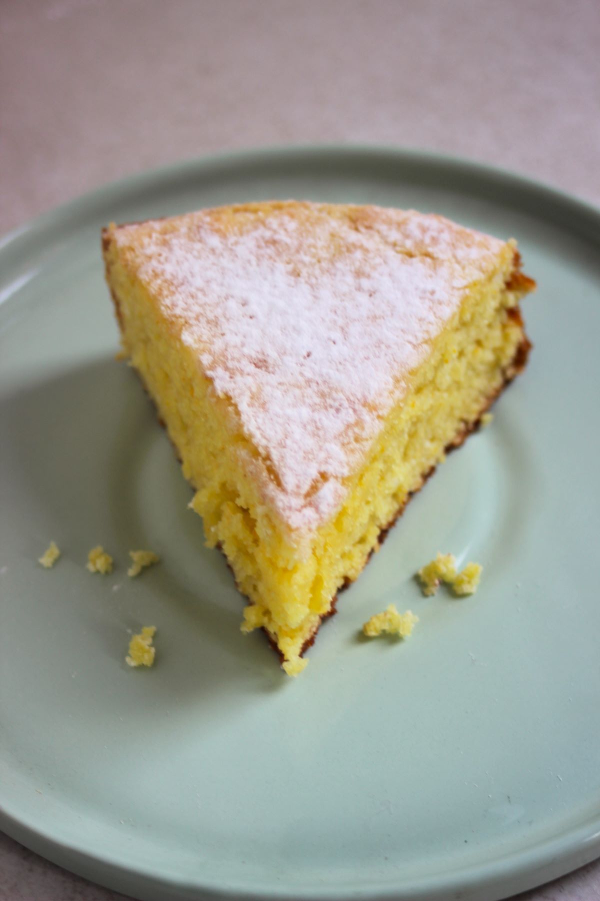 A portion of orange cake on an aqua-green plate.