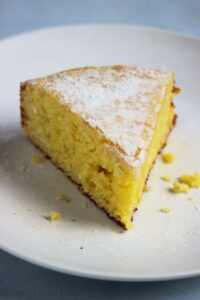 A portion of orange cake on white plate.