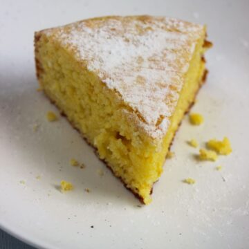 A portion of orange cake on white plate.