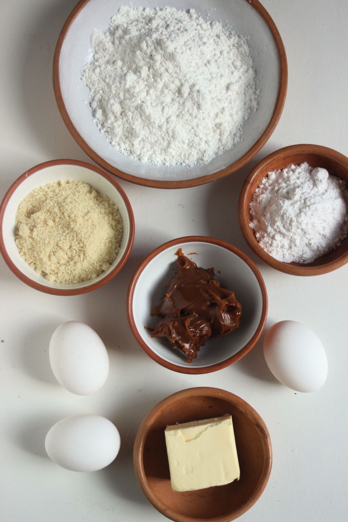 Gluten-free almond alfajores ingredients on a white surface seen from above.