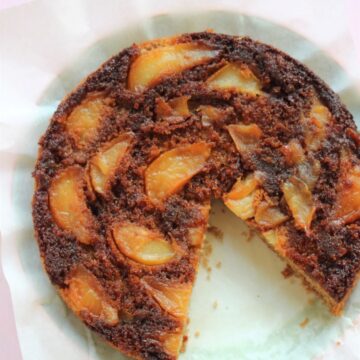 Pear upside-down cake without a slice, on a white surface seen from above.