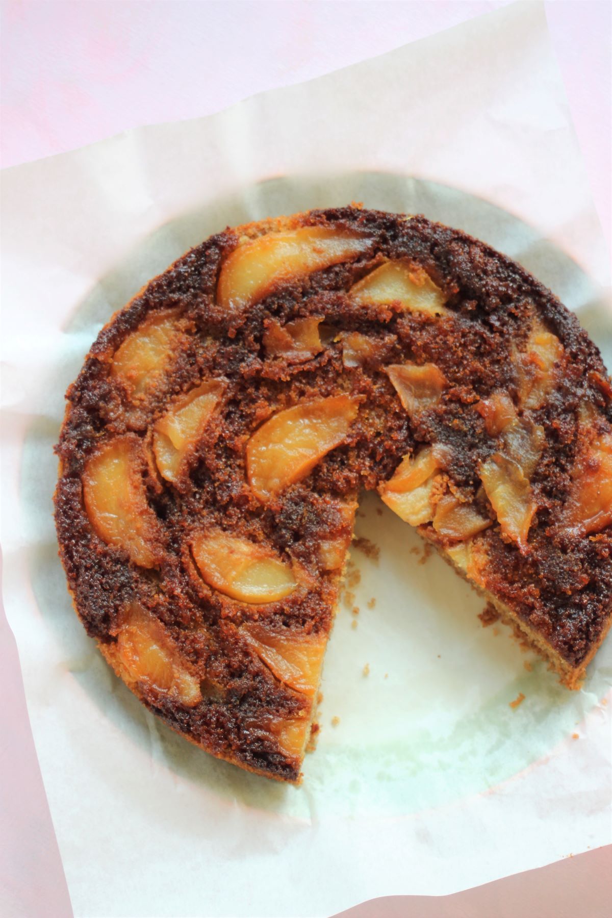 Pear upside-down cake without a slice, on a white surface seen from above.