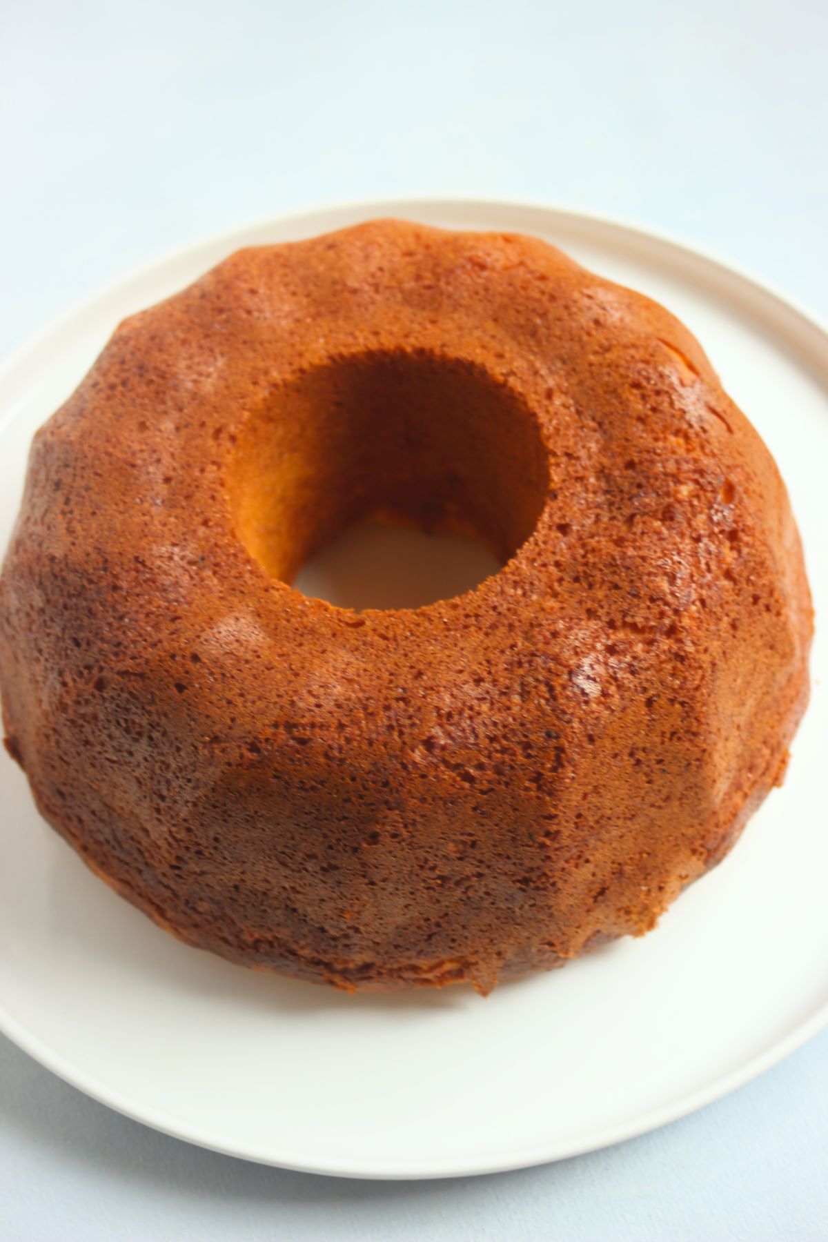 Gluten-free mandarin bundt cake without icing on a white plate.