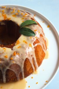 Gluten-free mandarin bundt cake topped with icing on a white plate.