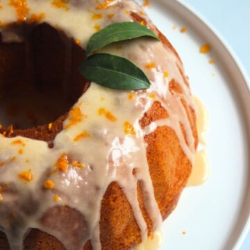 Gluten-free mandarin bundt cake topped with icing on a white plate.