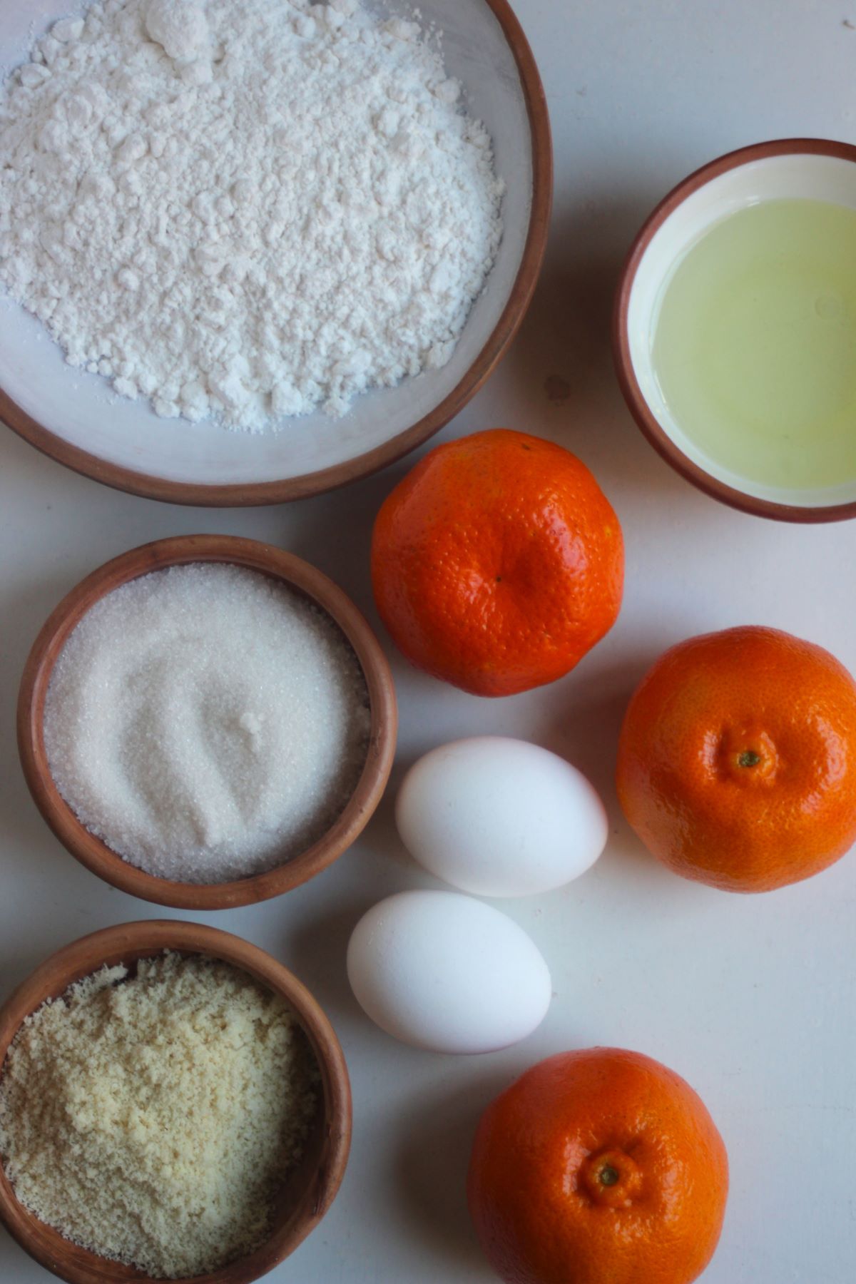 Mandarin bundt cake ingredients on a white surface seen from above.