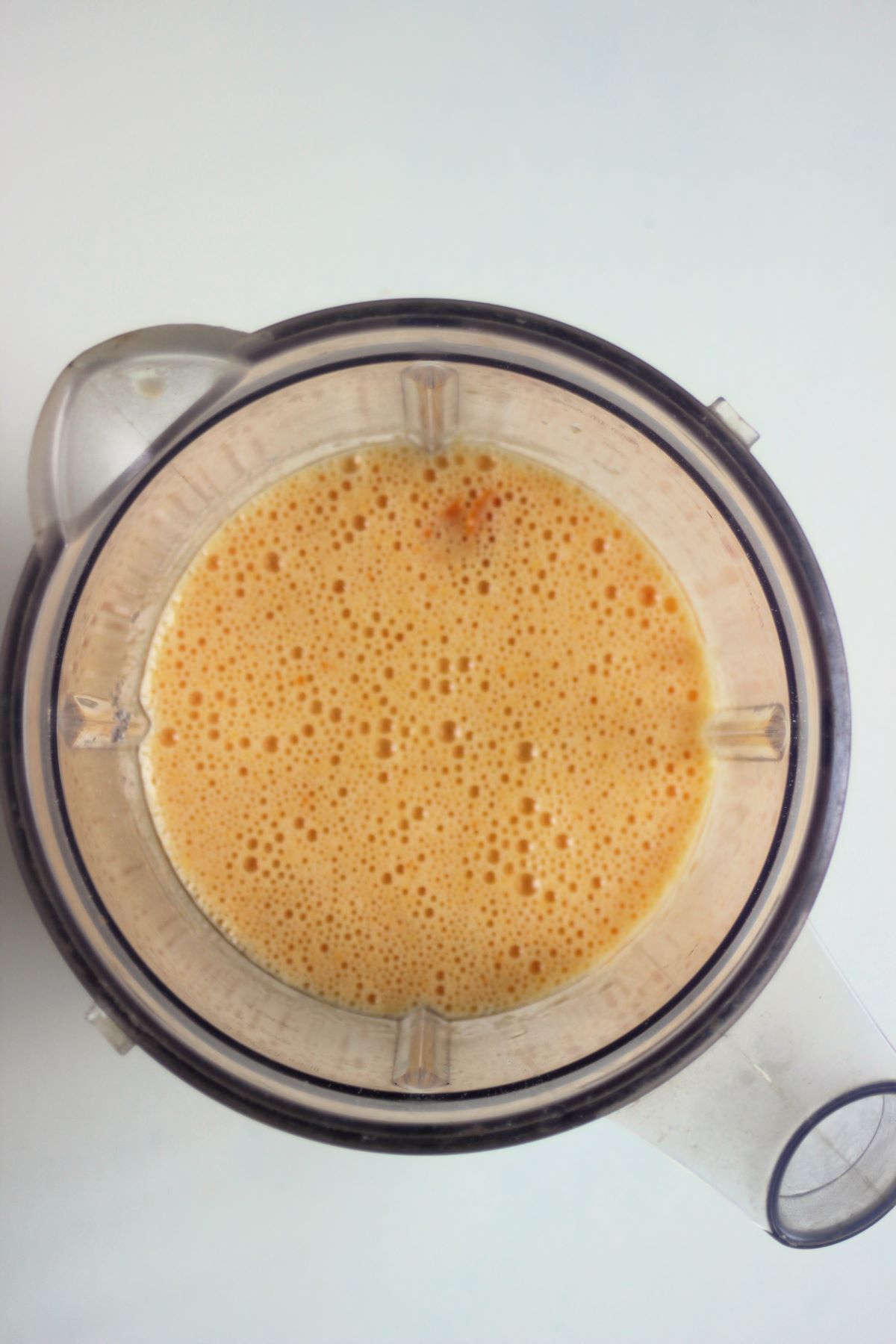 A blender with an orange liquid seen from above.