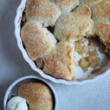 Apple cobbler and a small bowl with a portion of cobbler with a scoop of ice cream seen from above.