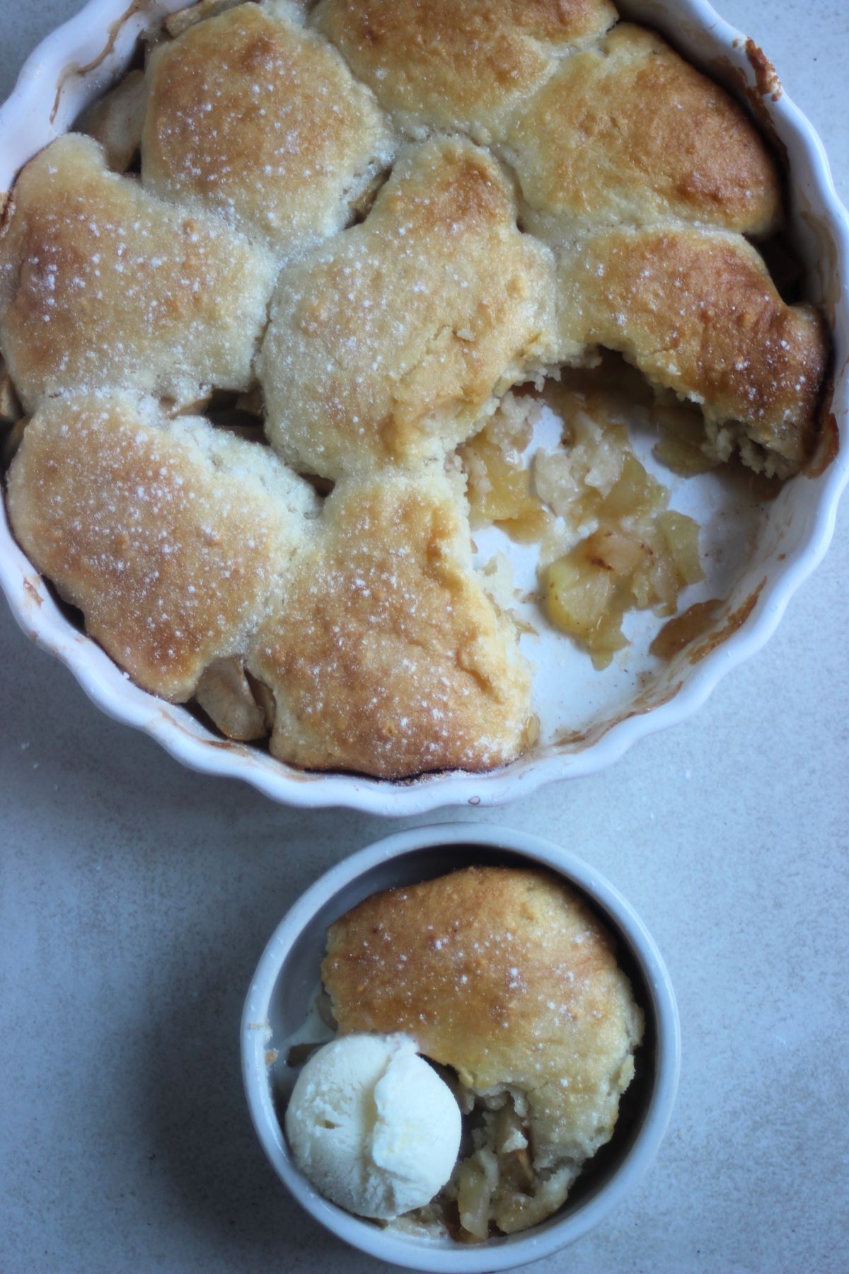 An apple cobbler and a small bowl with a portion of cobbler seen from above.