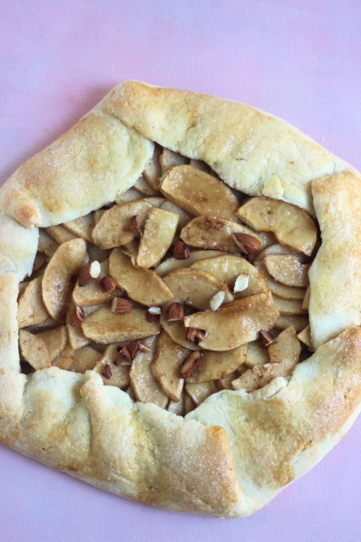 Apple galette on a pink surface seen from above.