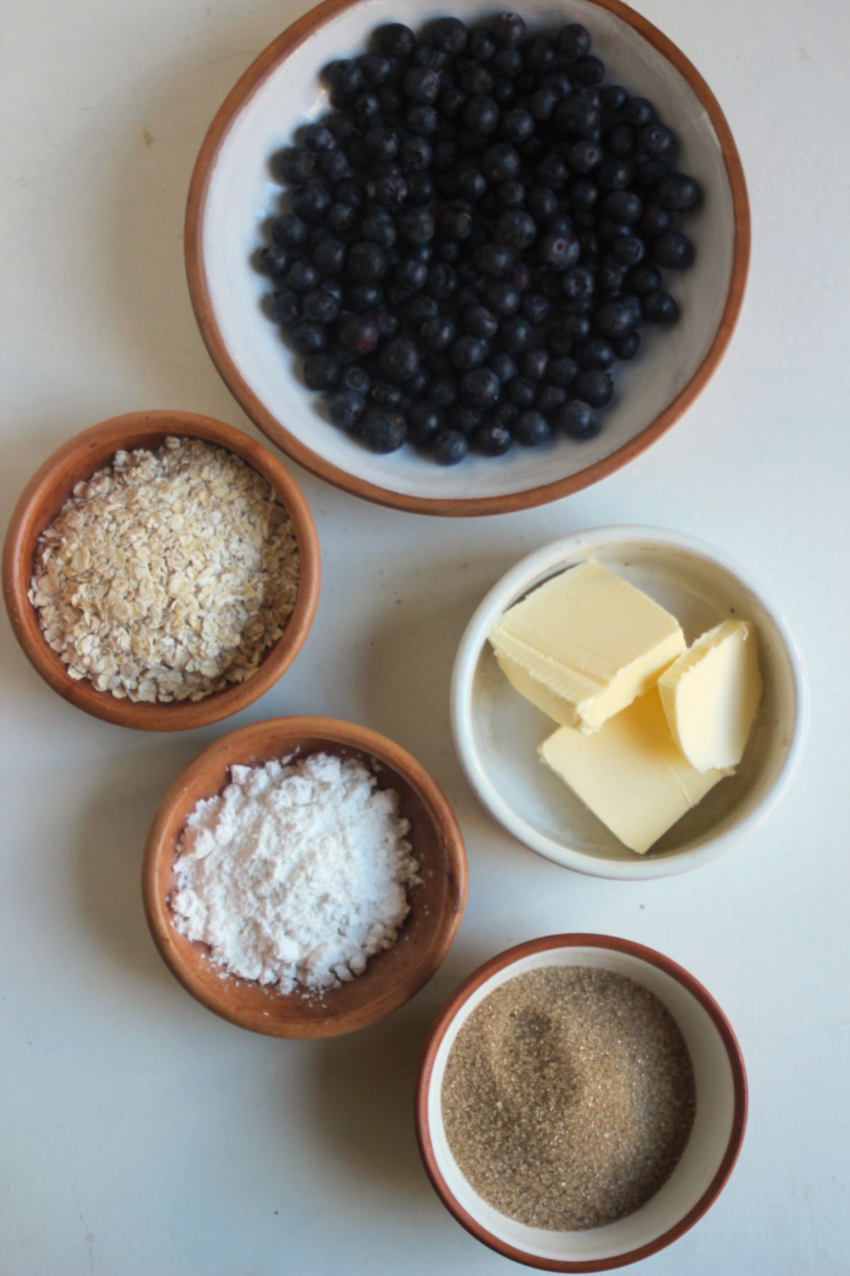 Blueberry crisp ingredients on a white surface seen from above.