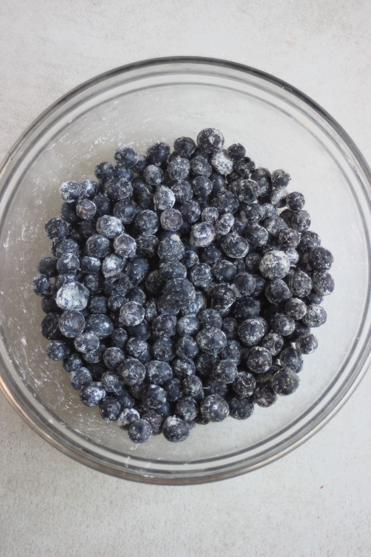 Glass bowl with blueberries and sugar.