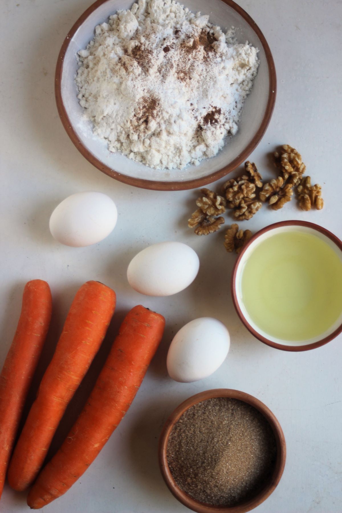 Carrot cake ingredients seen from above on a white surface.