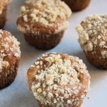 Apple crumb muffins on a white surface.