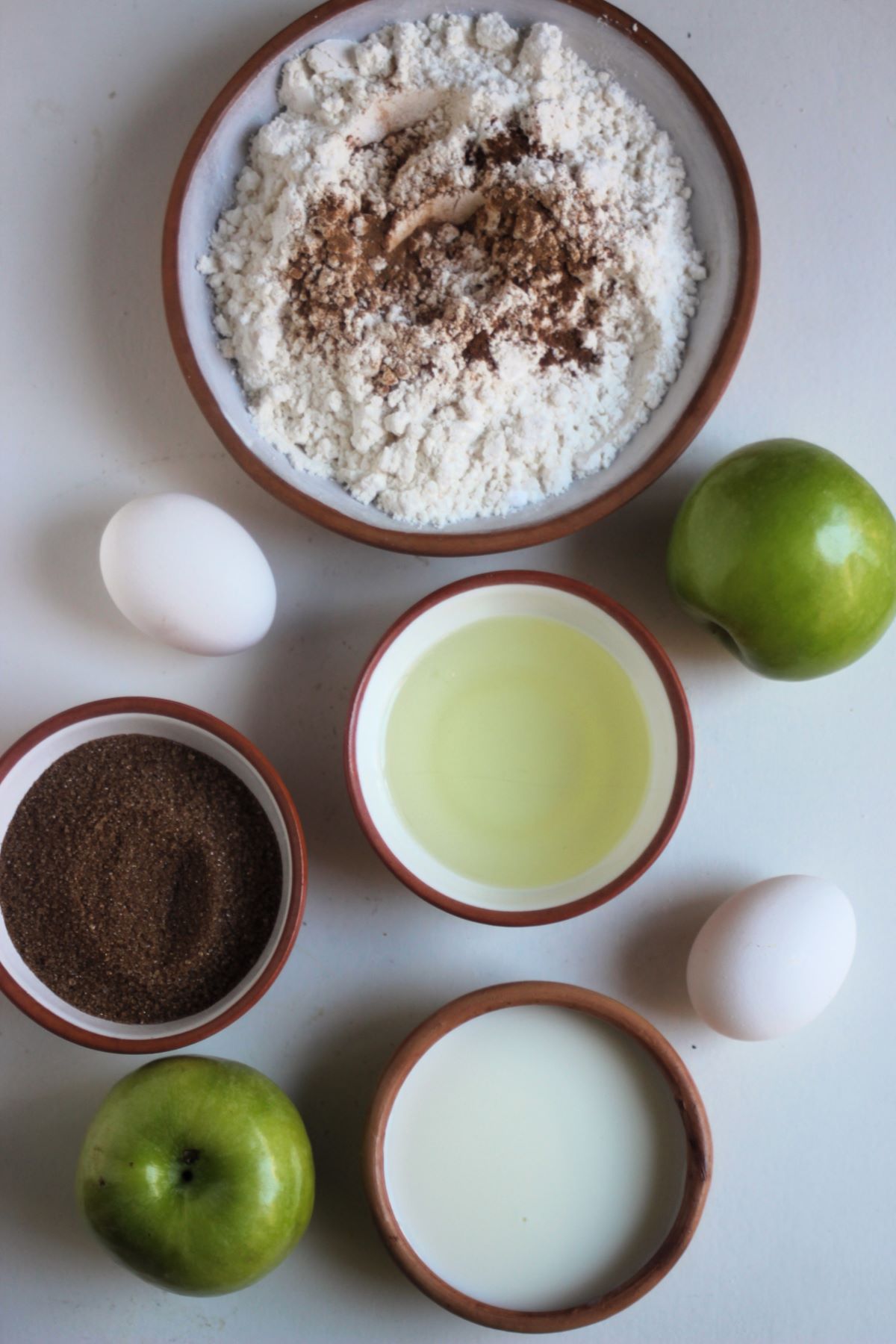 Apple crumb muffins ingredients on a white surface.