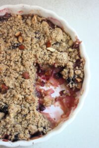 Apple crumble without a piece in a round baking dish seen from above.