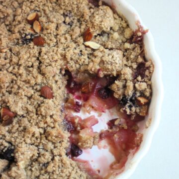 Apple crumble without a piece in a round baking dish seen from above.