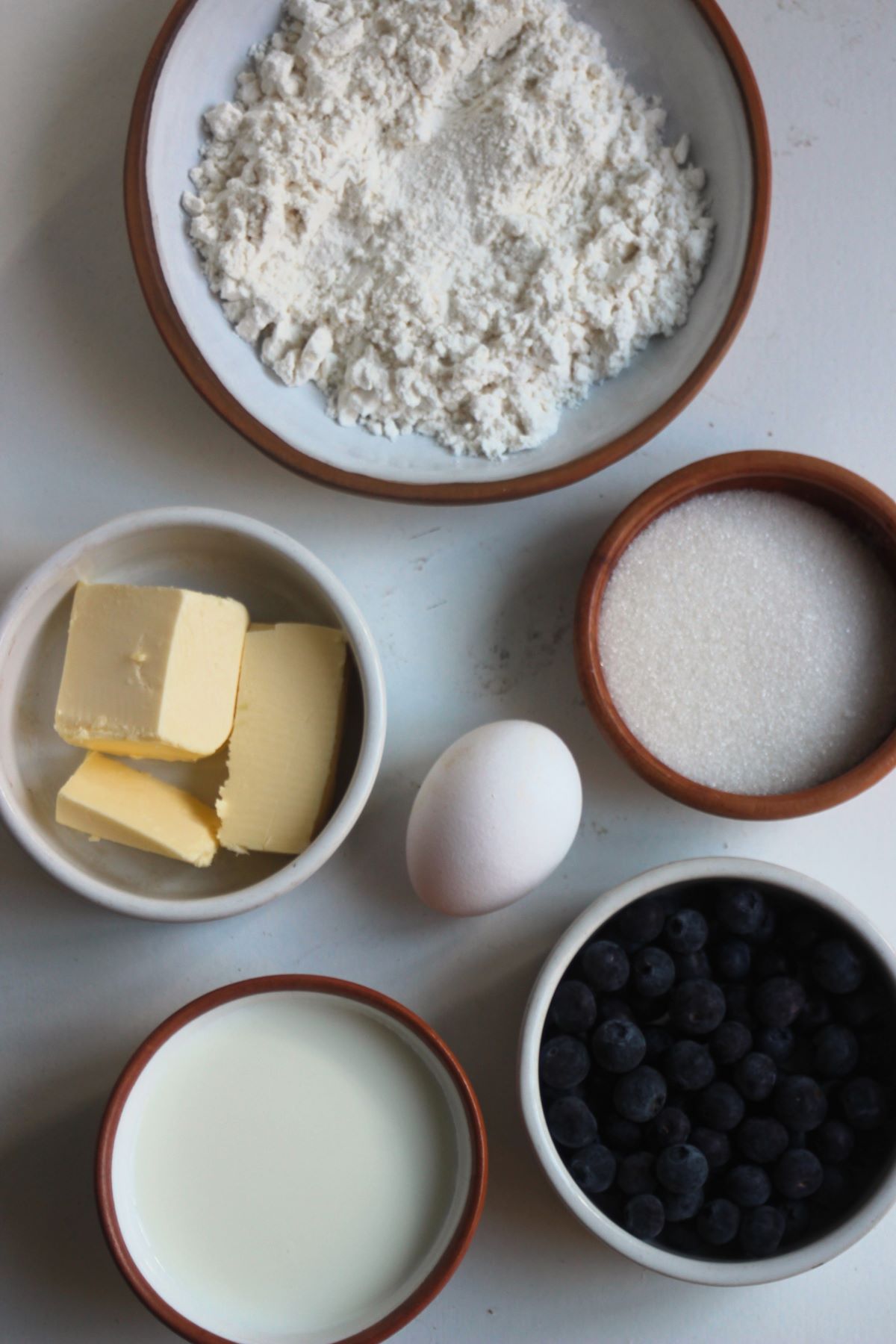 Blueberry scones ingredients on a white surface seen from above.