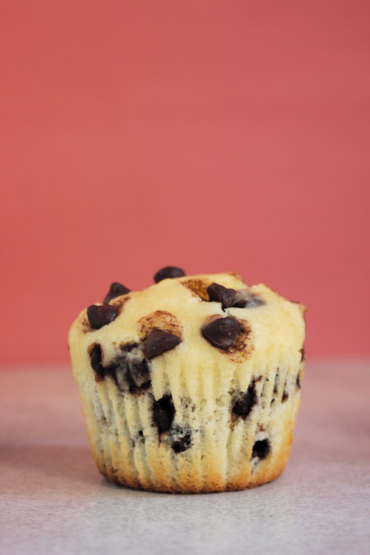 Chocolate chip muffin on a white surface, Pink background.