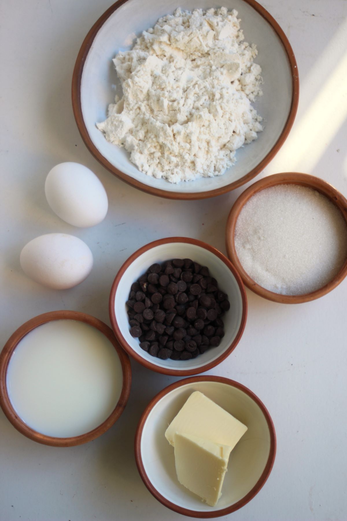 Chocolate chip muffins ingredients on a white surface seen from above.