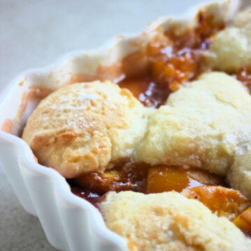 A part of a baking sheet with a peach cobbler seen from close,