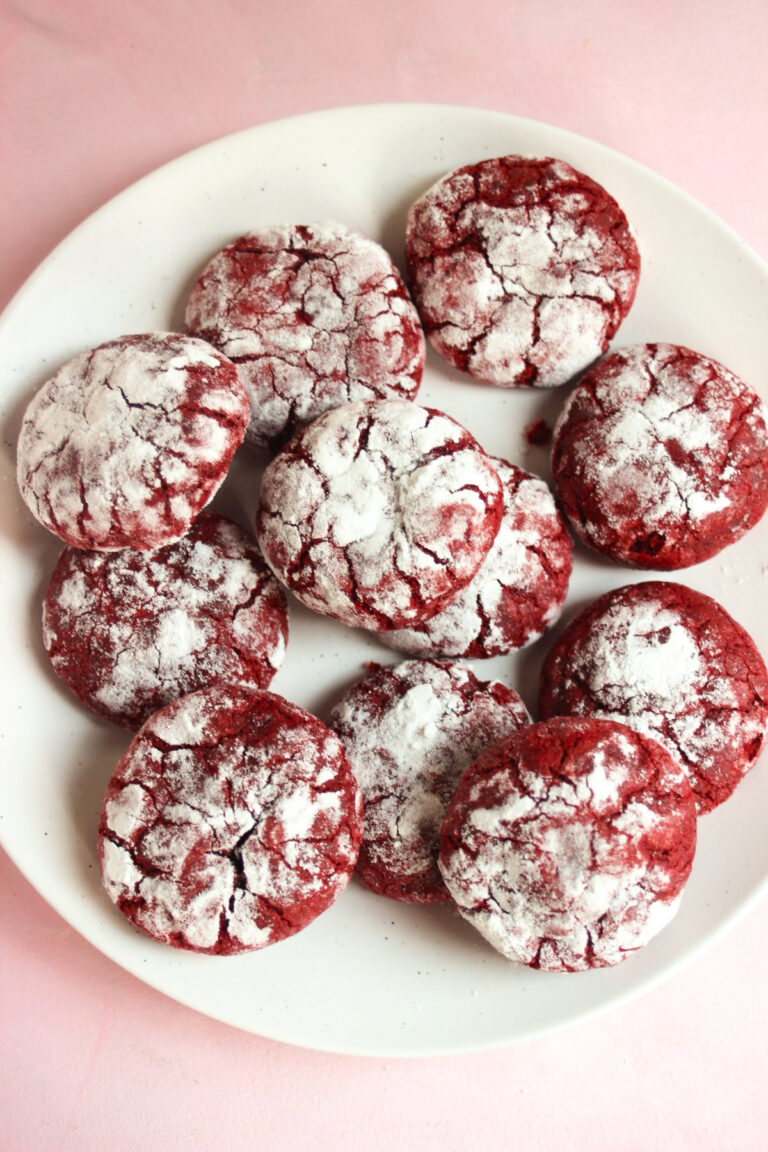 Many red velvet crinkle cookies on a pink plate.