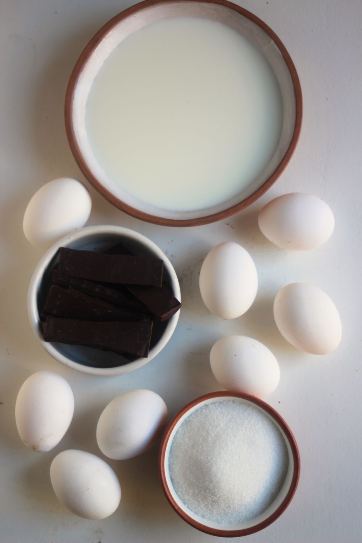 Chocolate flan ingredients on a white surface seen from above.