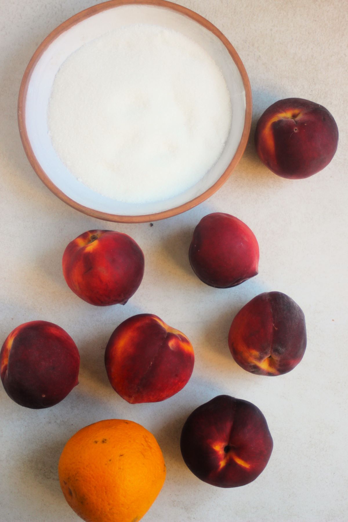 Peach jam ingrredients on a white surface seen from above.