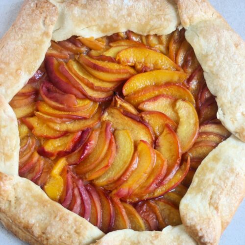 Peach galette on a white surface seen from above.