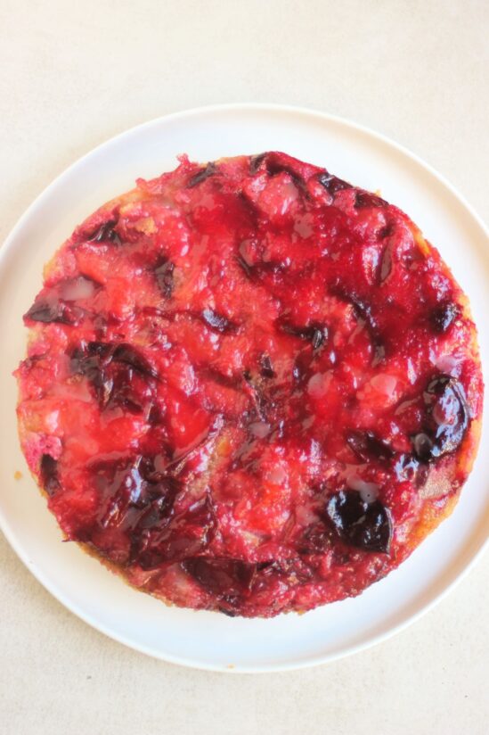 Plum upside down cake on white plate seen from above.