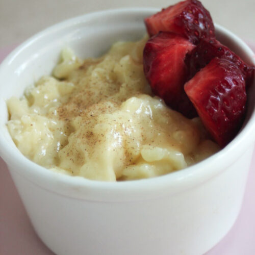 White ramekin with caramel rice pudding and fresh strawberries.