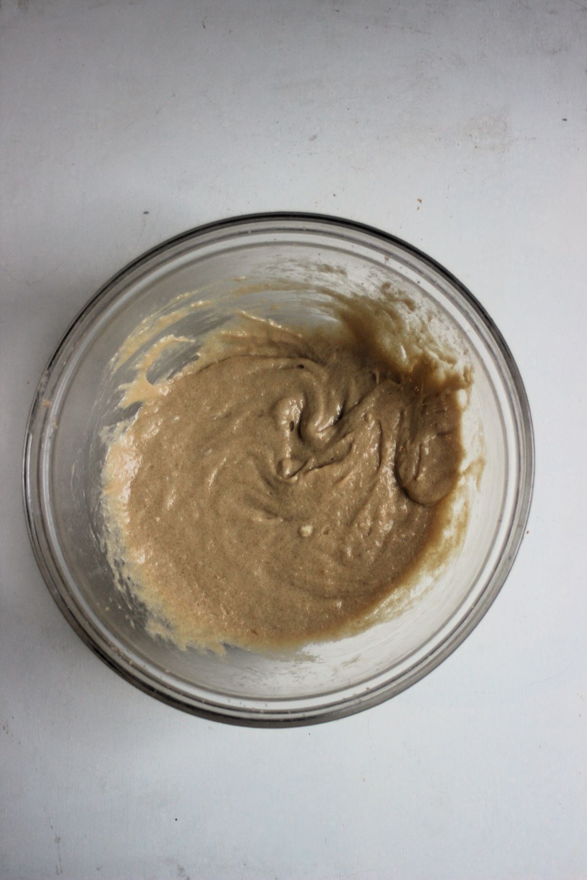 Glass bowl with a light brown mixture.